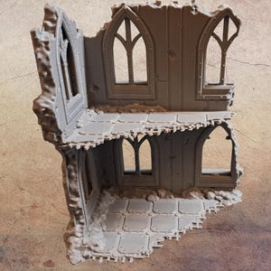 May include: A gray, ruined building model with arched windows and a tiled floor. The model has a weathered appearance, with sections of the walls and roof missing, suggesting damage or decay. Ideal for tabletop gaming or miniature displays.
