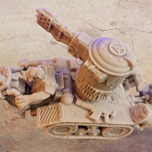 Op de afbeelding: Een beige miniatuur tankmodel met een groot kanon en ingewikkelde mechanische details. Het model heeft een rupsbandbasis, een grote cilindrische toren en diverse andere componenten, die een gedetailleerd, industrieel ontwerp laten zien.