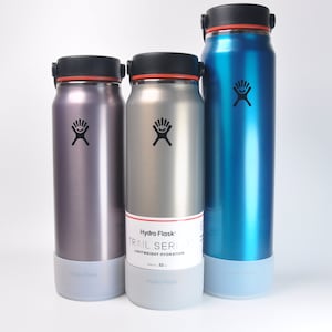 May include: Three stainless steel water bottles with different colored lids and bodies. The bottles are labeled "Hydro Flask" and "Trail Series Lightweight Hydration". The bottles are 32 oz.