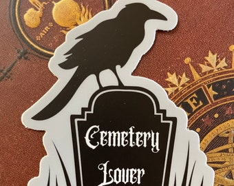 May include: Black and white sticker of a crow perched on a tombstone with the text "Cemetery Lover".