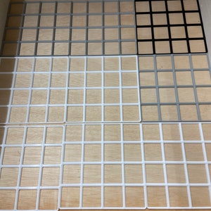 May include: A wooden drawer with several square grid organizers in various colors: gray, black, and white. The grids are made of plastic and are designed to fit inside the drawer, providing organization and storage.