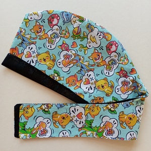 May include: A turquoise blue scrub hat with a black elastic band. The hat is covered in a whimsical pattern of cartoon animals, hearts, and lightning bolts.