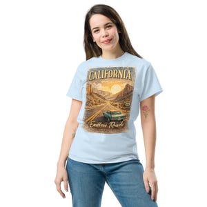 Könnte beinhalten: Hellblaues T-Shirt mit einem Vintage-California-Reise-Design. Die Grafik zeigt eine Straße, ein klassisches Auto, Berge und den Text "CALIFORNIA Endless Roads Since 1993".