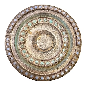 Puede incluir: Un plato decorativo redondo de estilo antiguo con círculos concéntricos. El plato presenta un acabado dorado metálico texturizado con detalles en azul claro y verde. El borde exterior está bordeado con pequeñas piedras redondas de color azul claro.