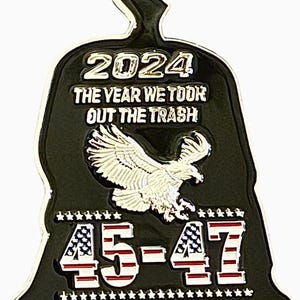 May include: A black and green metal pin shaped like a trash bag with a bald eagle and the text "2024 The Year We Took Out The Trash 45-47" in silver lettering.
