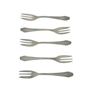 Op de afbeelding: Vijf zilverkleurige vorken met elk drie tanden, verticaal geplaatst tegen een witte achtergrond. De vorken hebben decoratieve handvatten en zijn waarschijnlijk voor het serveren van hapjes of desserts.