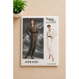 May include: A Vogue Patterns sewing pattern envelope for an Anne Klein jumpsuit, labeled 1916. The front features a photograph of a person wearing a dark olive jumpsuit with a wrap-style bodice and a black belt, alongside a fashion illustration.
