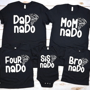 Könnte beinhalten: Eine Sammlung schwarzer T-Shirts und ein Baby-Body mit weißem Text und einer Wirbelsturm-Grafik. Die Shirts zeigen "Dad nado", "Mom nado", "Four nado" und "Bro nado". Der Body trägt die Aufschrift "Sis nado".