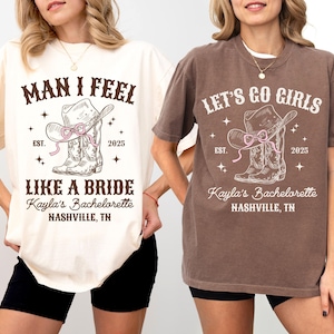 May include: Two white t-shirts with brown text and graphics. The first shirt says "Man I Feel Like A Bride Kayla's Bachelorette Nashville, TN" with a drawing of cowboy boots and a hat. The second shirt says "Let's Go Girls Kayla's Bachelorette Nashville, TN" with a drawing of cowboy boots and a hat.