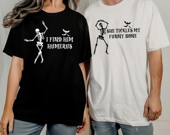 May include: Black and white t-shirts with skeleton graphics and text. One shirt is black with the text "I FIND HIM HUMERUS". The other shirt is white with the text "SHE TICKLES MY FUNNY BONE". Both shirts have a bat graphic.