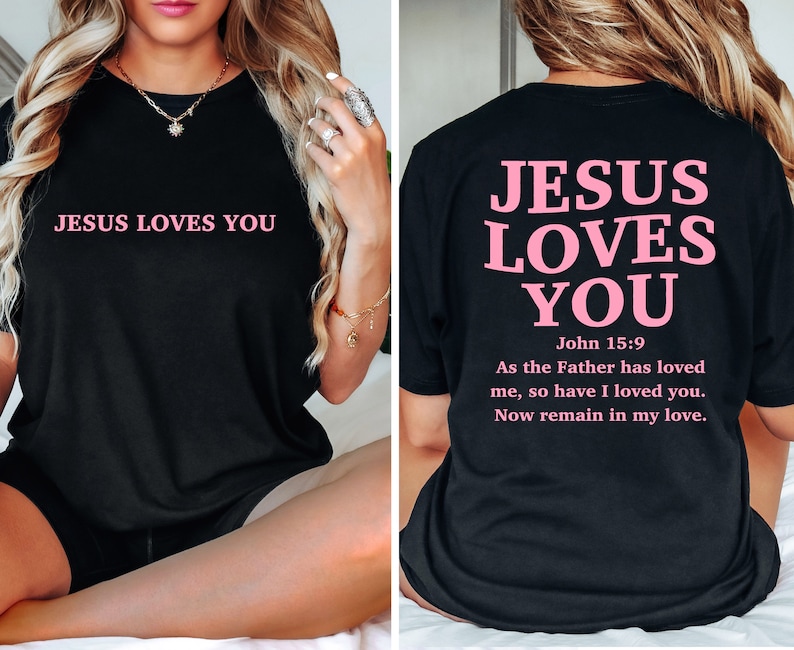 May include: Black t-shirt with the text "JESUS LOVES YOU" in pink on the front and the same text in pink with a Bible verse on the back.