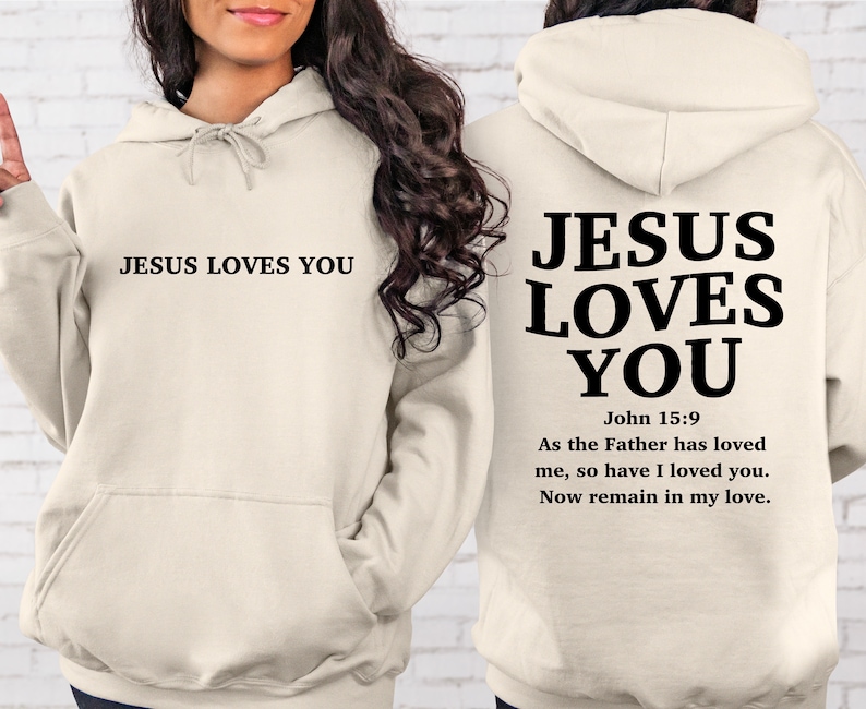 May include: A cream-colored hoodie with the text "JESUS LOVES YOU" on the front and the text "JESUS LOVES YOU" with the Bible verse "John 15:9 As the Father has loved me, so have I loved you. Now remain in my love." on the back.