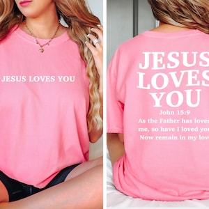 May include: Pink t-shirt with the text "JESUS LOVES YOU" on the front and the text "JESUS LOVES YOU" with the Bible verse John 15:9 on the back.
