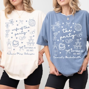 May include: Two oversized t-shirts, one ivory and one blue, with matching graphic designs. The ivory shirt reads "wife of the party" and the blue shirt reads "the party". Both shirts feature a Scottsdale, AZ, EST. 2025 design.