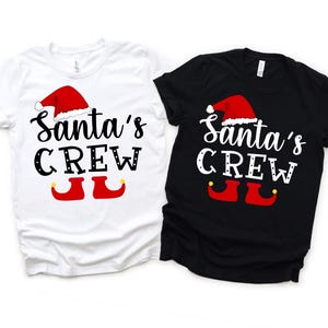 Puede incluir: Dos camisetas de manga corta, una blanca y otra negra, cada una con el texto "Santa's CREW" en una fuente caprichosa. El diseño incluye un gorro de Papá Noel rojo, letras negras y zapatos de elfo rojos con detalles amarillos, para Navidad.