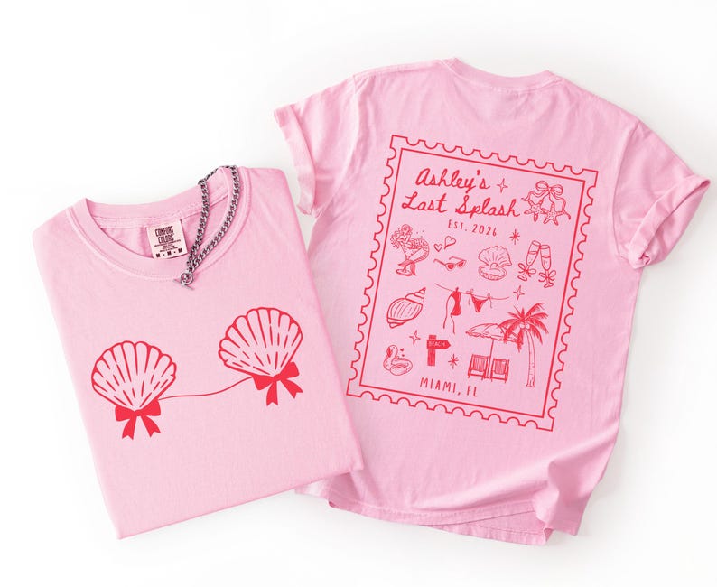 May include: Two pink t-shirts. One features a red seashell design with bows, and a silver chain necklace. The other shirt has a red stamp design with text that reads "Ashley's Last Splash" and "Miami, FL".