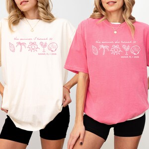 May include: Two oversized t-shirts, one cream and one pink, with the text "the summer I turned 30" and beach-themed graphics. The text "MIAMI, FL 2026" is also printed on the shirts. The shirts are paired with black shorts.