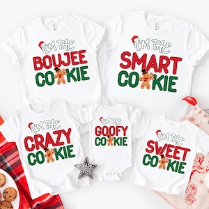 May include: White t-shirts with Christmas-themed text and gingerbread man graphics. The shirts read "I'm the Boujee Cookie", "I'm the Smart Cookie", "I'm the Crazy Cookie", "I'm the Goofy Cookie", and "I'm the Sweet Cookie".