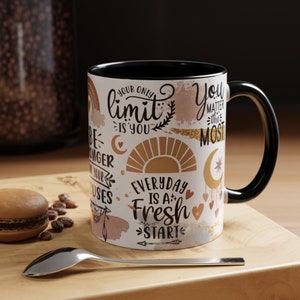 Puede incluir: Taza de café de cerámica blanca con asa negra. La taza tiene un diseño colorido con citas inspiradoras e ilustraciones, incluyendo un sol, una luna y flechas. El texto en la taza dice "Your only limit is you", "Everyday is a fresh start", y "You matter the most".
