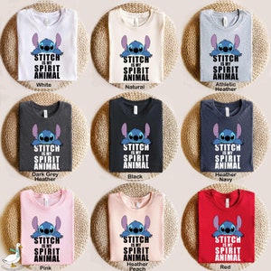 Op de afbeelding: Negen verschillende kleur t-shirts met een blauw Stitch-personage uit de Disney-film Lilo & Stitch. De tekst op de shirts luidt "Stitch is my spirit animal".