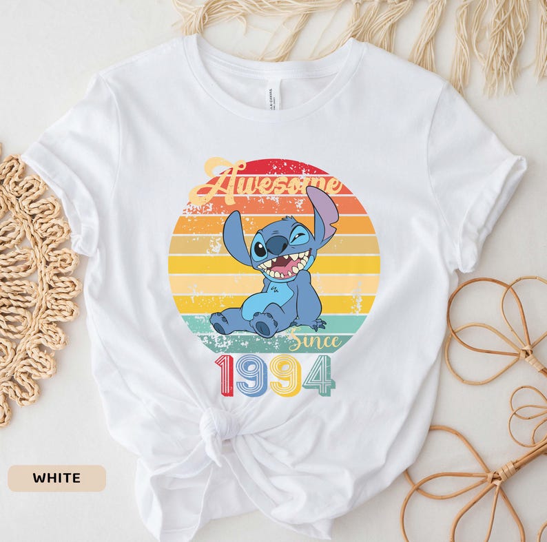 May include: White t-shirt with a vintage-style graphic of Stitch from Lilo & Stitch. The graphic says "Awesome Since 1994".