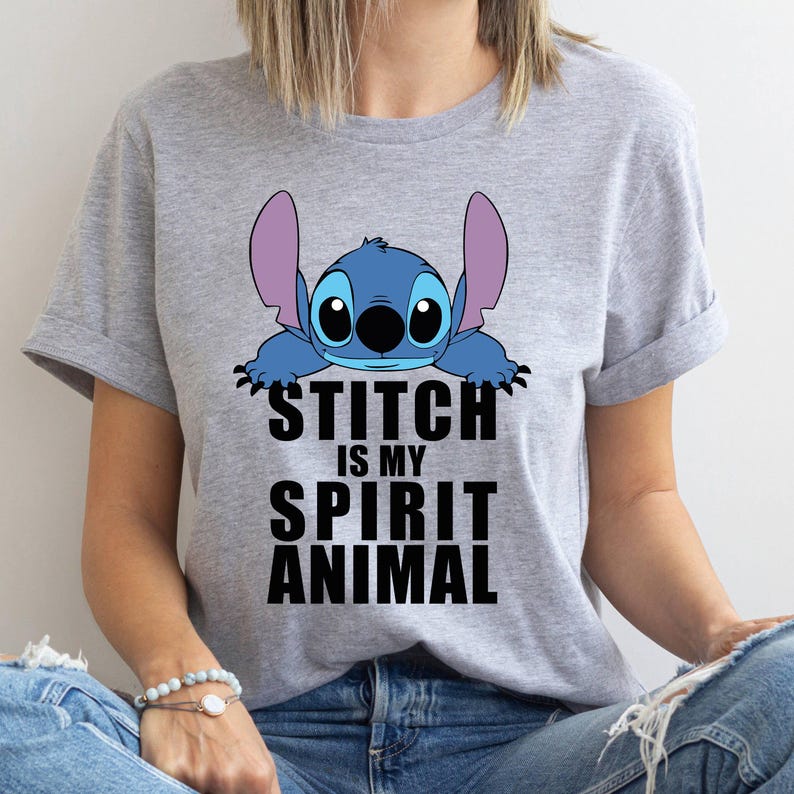 Op de afbeelding: Grijs T-shirt met een blauw Stitch-personage uit Lilo & Stitch. De tekst "Stitch is my spirit animal" is in zwart onder het personage gedrukt.