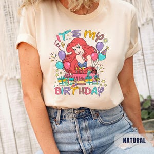 Puede incluir: Una camiseta beige claro con una imagen de dibujos animados de Ariel de La Sirenita. La imagen incluye un pastel de cumplea&ntilde;os, regalos, globos y el texto "Es mi cumplea&ntilde;os".