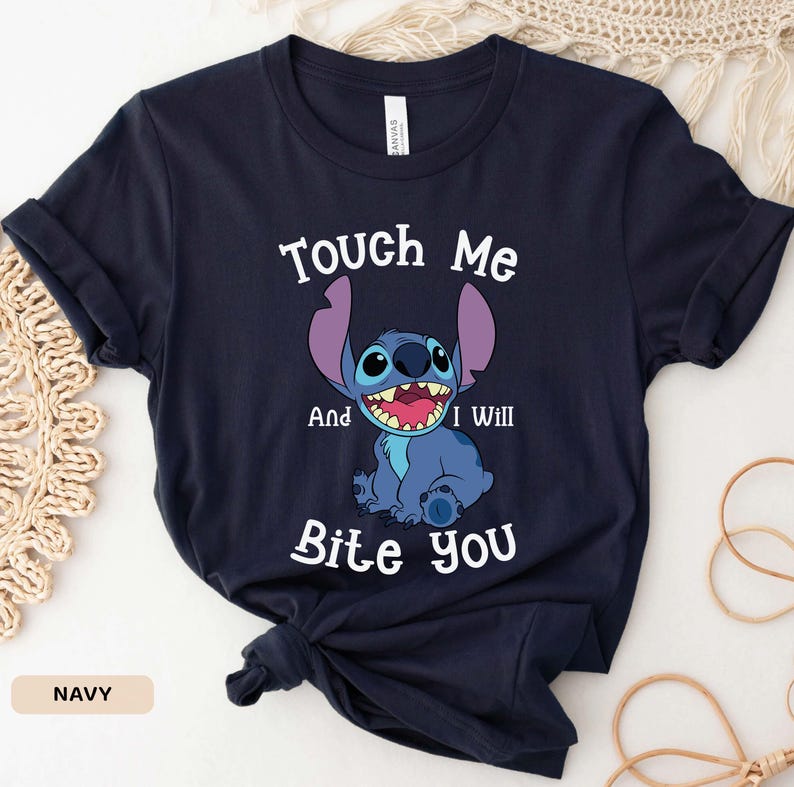 May include: A navy blue t-shirt with a cartoon Stitch character from Lilo & Stitch. The text "Touch Me And I Will Bite You" is printed on the shirt.