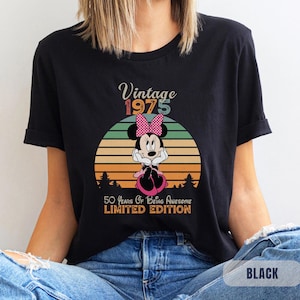 May include: Black t-shirt with a vintage 1975 design featuring a cartoon image of Minnie Mouse with a pink bow. The text reads "Vintage 1975 50 Years of Being Awesome Limited Edition".