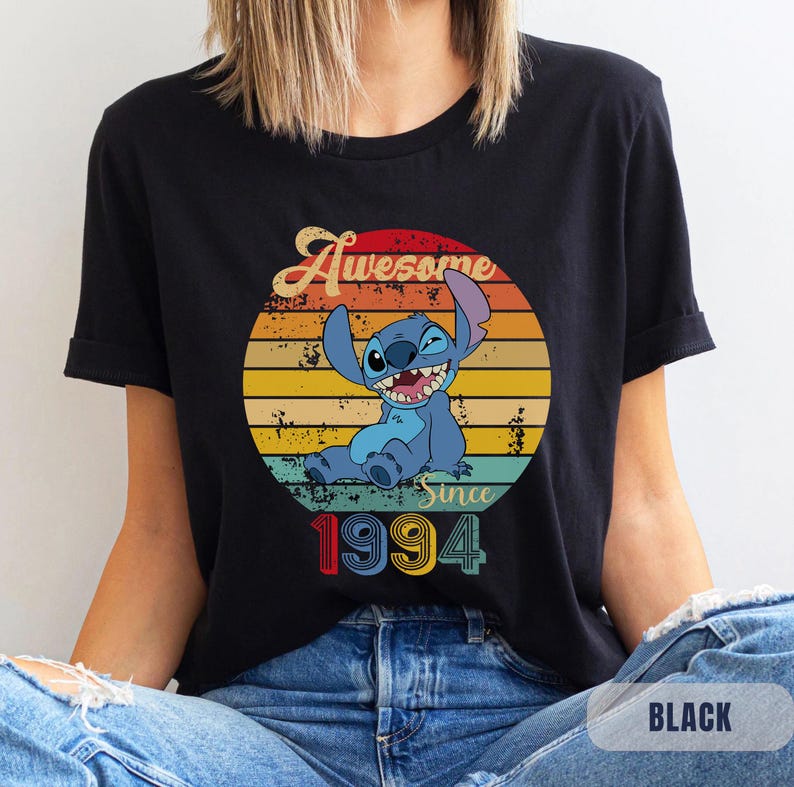 May include: Black t-shirt with a retro-style graphic of a blue Stitch character from Lilo & Stitch. The graphic says "Awesome Since 1994".
