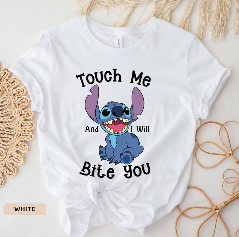 May include: White t-shirt with a blue Stitch character from Lilo & Stitch. The text "Touch Me And I Will Bite You" is printed on the shirt.