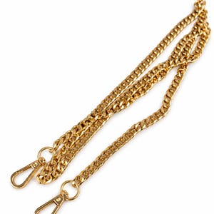 May include: A gold-toned metal chain strap featuring a curb link design. The chain is equipped with two matching gold-toned lobster claw clasps at each end, designed for attachment to bags or accessories, providing a secure and functional connection.
