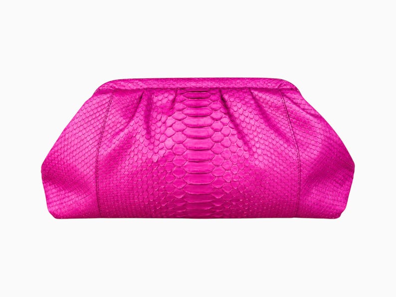 May include: A bright fuchsia clutch bag featuring a textured snakeskin pattern. The bag has a rounded, pleated top frame design with a smooth, curved silhouette and a consistent, vibrant pink color throughout the entire exterior surface.