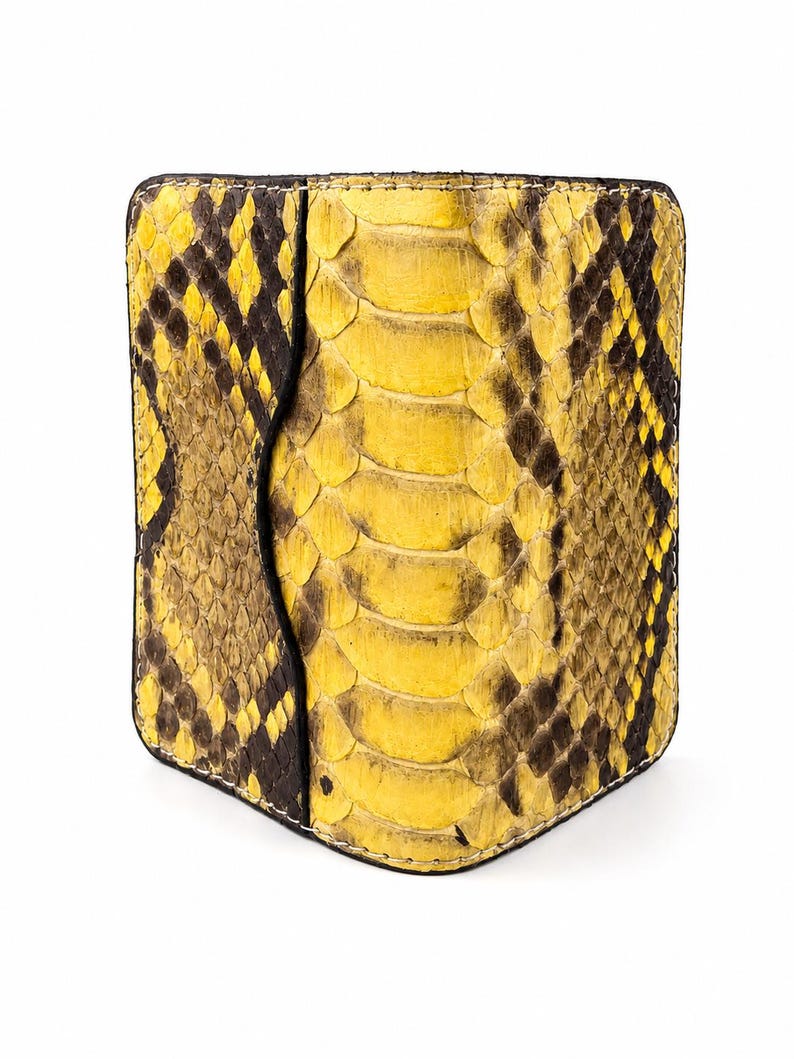 May include: A rectangular wallet featuring a vibrant yellow and black snakeskin pattern. The exterior displays a textured scale design with a distinct vertical panel on the left side, finished with visible stitching along the rounded edges.