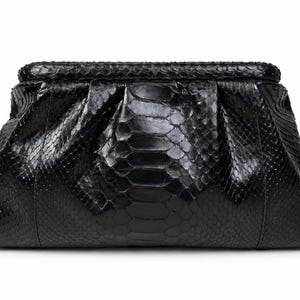 May include: A black clutch bag featuring a textured snakeskin pattern with a glossy finish. The bag has a structured frame, a hinged top closure, and a gathered, pleated design that creates a soft, voluminous shape across the front surface.