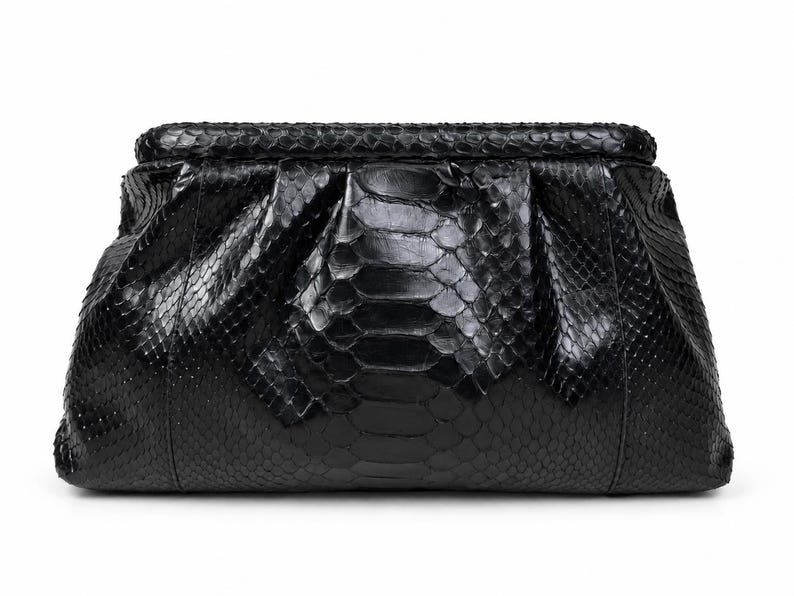 May include: A black clutch bag featuring a textured snakeskin pattern with a glossy finish. The bag has a structured frame, a hinged top closure, and a gathered, pleated design that creates a soft, voluminous shape across the front surface.
