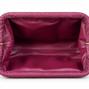 Pode incluir: Uma bolsa clutch magenta com um padr&atilde;o exterior texturizado semelhante a escamas e um forro interior liso de cor magenta s&oacute;lida. A bolsa retangular possui uma abertura de moldura articulada com pequenas dobradi&ccedil;as met&aacute;licas douradas.