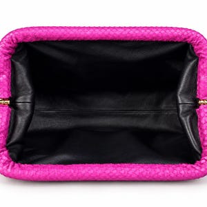 May include: A bright fuchsia clutch bag with a textured snakeskin-patterned exterior and a wide, open rectangular frame. The interior is lined with smooth black leather, and the frame features small gold-toned metal hinges on both sides.