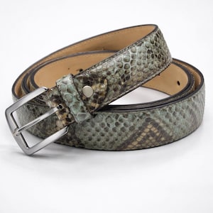 May include: A coiled belt with a snakeskin pattern in shades of green, brown, and tan. The belt has a silver-colored buckle and a leather interior. The belt is a fashion accessory.