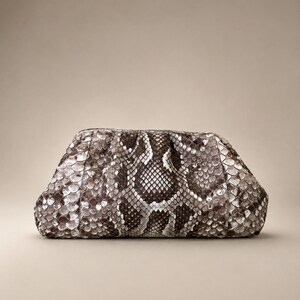 May include: A structured clutch bag featuring a detailed snakeskin pattern in shades of brown, gray, and white. The bag has a rounded, gathered top frame design with a textured, scale-like surface throughout the exterior, creating a distinct visual pattern.