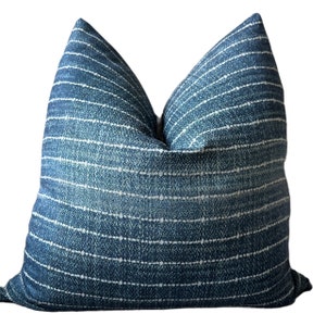 May include: A blue and white striped throw pillow with a subtle pattern. The pillow is made of a soft, textured fabric.