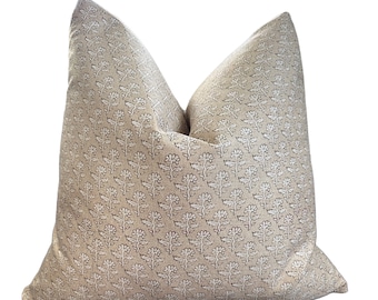 May include: A beige pillow with a white and brown floral pattern.