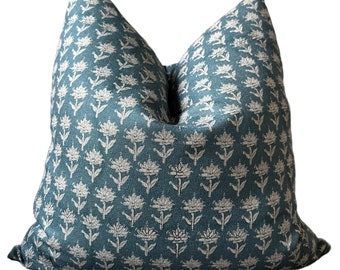 Könnte beinhalten: Ein quadratisches Dekokissen mit einem tiefen blaugrünen Stoffbezug und einem sich wiederholenden Muster aus kleinen, hellbeigen Blumenmotiven. Das Kissen hat ein deutlich sichtbares Webmuster sowie eine weiche, pralle Form mit einer leichten Vertiefung.