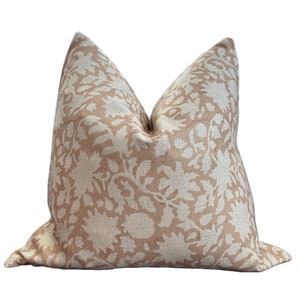 May include: A beige pillow with a white floral pattern. The pillow is made of a soft, textured fabric.