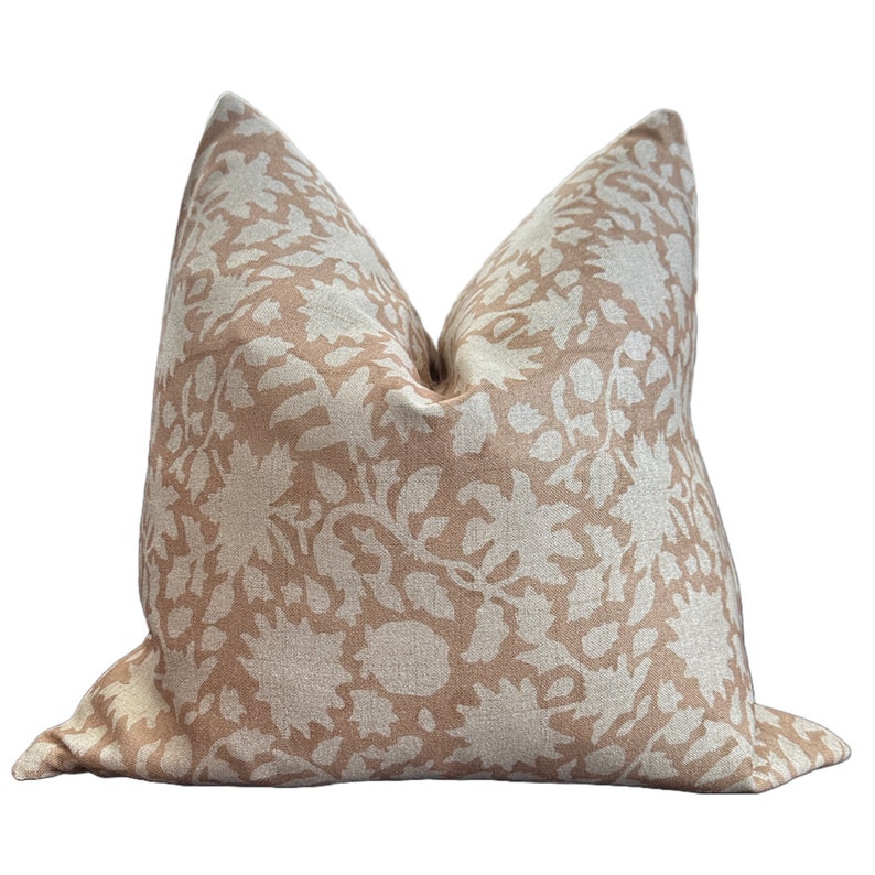 May include: A beige pillow with a white floral pattern. The pillow is made of a soft, textured fabric.