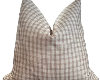 May include: A square scatter cushion featuring a light brown and white gingham check pattern. The fabric has a visible woven texture and the cushion is plumped at the top to create two distinct peaks, showcasing a soft, filled construction.