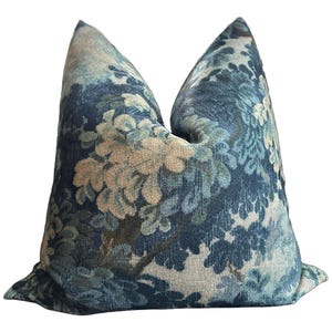 Puede incluir: Una almohada de tiro con estampado floral azul y crema con una tela texturizada.