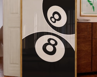 May include: A framed print with a yin-yang design, incorporating two number 8 pool balls in black and white. The artwork is displayed on a wooden floor. Other framed art pieces are visible in the background.