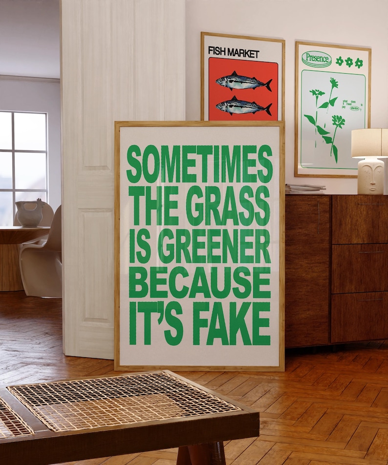 May include: A framed poster with the text "SOMETIMES THE GRASS IS GREENER BECAUSE IT'S FAKE" in green block letters. Two other framed posters are visible, one with fish and the words "FISH MARKET", and another with green floral designs.