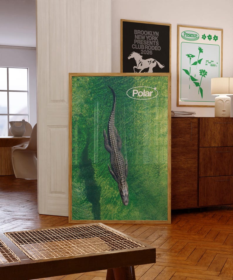 May include: A framed poster featuring a top-down view of an alligator in a green environment. The word "Polar" is in a white oval at the top. Two other framed posters are visible, one with a horse graphic and the other with green floral designs.